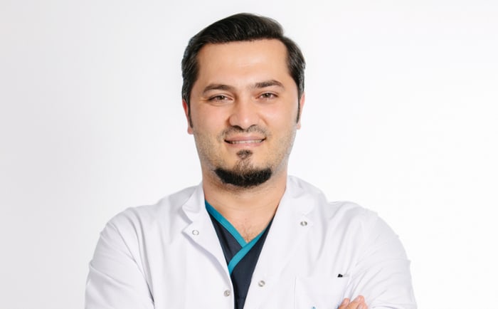 Dr Balwi lächelnd vor einem grauen Hintergrund